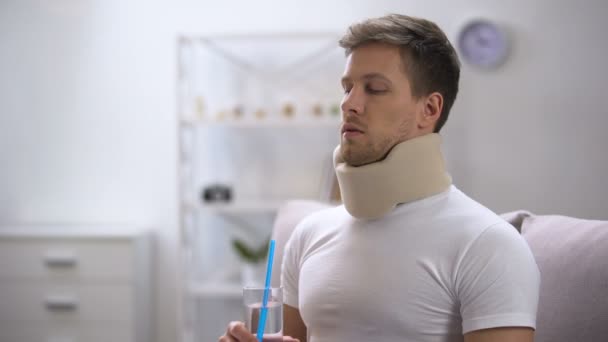 Homme en mousse col cervical essayant de boire de l'eau en verre avec de la paille, pauvre tentative — Video