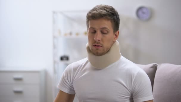 Displeased man in foam cervical collar suddenly feeling pain in neck, trauma — Stock Footage Displeased man in foam cervical collar suddenly feeling pain in neck, trauma Video Clip