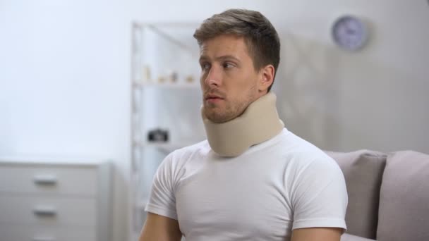 Sad male in foam cervical collar hardly breathing, feeling upset after trauma — Stock Video