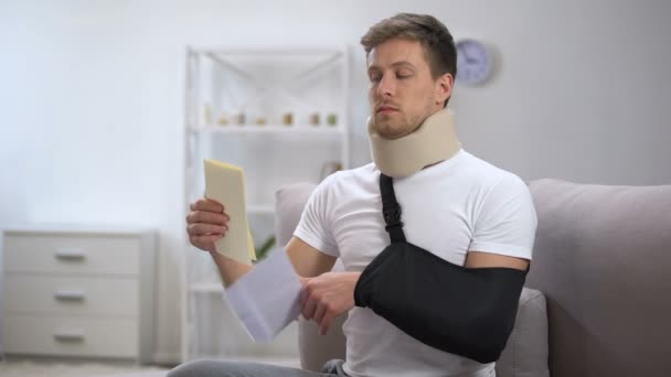 Man in Foam cervicale kraag en arm Sling lezing medische rekening, schokkende prijs — Stockvideo