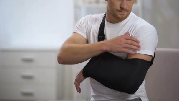 Man wearing arm sling feeling pain in shoulder, result of trauma, orthopedics — Stock Video