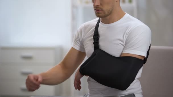Paciente masculino ajustando estilingue do braço em posição adequada, reabilitação após trauma — Vídeo de Stock