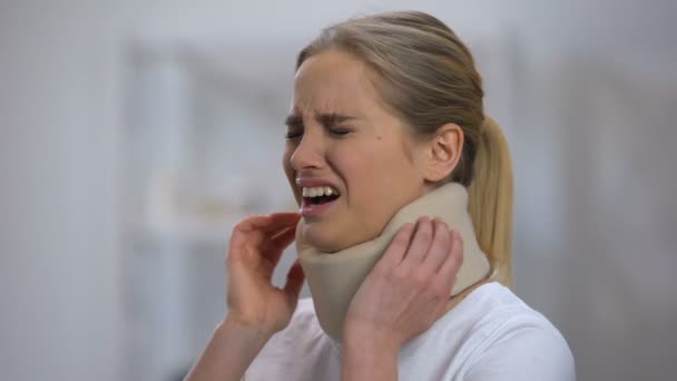 Injured female in foam cervical collar suddenly feeling sharp pain in neck — Stock Video