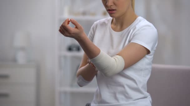 Mujer que aplica la urdimbre elástica del codo después de traumatismo deportivo ortopedia y atención médica — Vídeo de stock