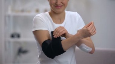 Dirsek dolgulu ortez uygulayan kadın, spor yaralanması sonrası ağrı hisseder, ortopedi