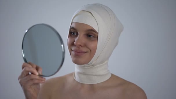 Nő headwrap nézi tükör elmélkedés, elégedett a plasztikai sebészet — Stock videók