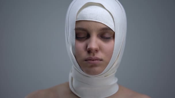 Female patient in headwrap looking to camera, rehabilitation after car accident — Stock Video