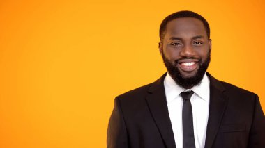 Resmi takım elbise li büyüleyici afro-amerikan adam gülümseyerek ve kamera şablonu arıyor