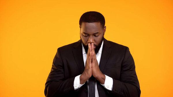 Black man in formal suit praying for successful negotiations important interview