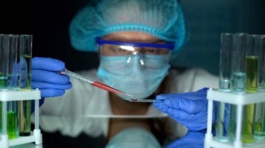 Araştırmacı, sıvı özellikleri okuyan, test camı üzerinde turuncu madde damlama