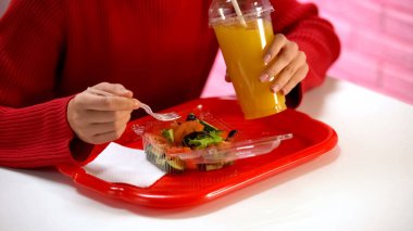 Kırmızı pullover kadın portakal suyu içme ve kafede sebze salatası yeme