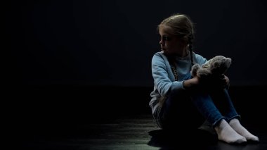 Oyuncak ayı yetim etrafa bakıyor, karanlık odada tek başına oturmak ile küçük kız