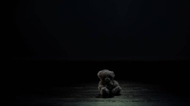 Teddy bear toy in dark room, loneliness and lost childhood concept, sadness clipart