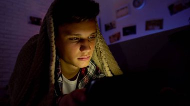 Uyku, yerine sekmesinde Internet sörf yorgun genç battaniyenin altında yalan