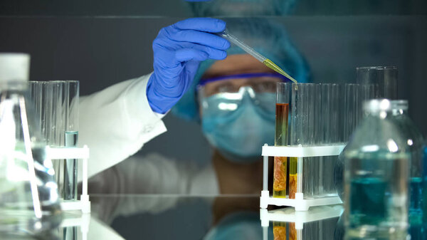 Lab assistant dripping chemical liquid in tube with meat sample, food quality