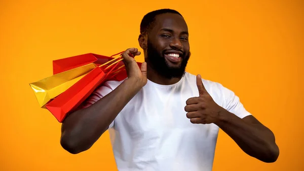 Μαύρος Άνδρας Κρατώντας Τσάντες Για Ψώνια Και Δείχνει Τους Αντίχειρες — Φωτογραφία Αρχείου
