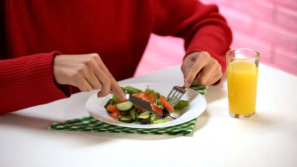 女士吃蔬菜沙拉叉和刀 新鲜的橙汁在桌子上 — 图库照片