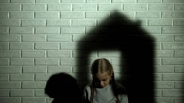 House shadow on wall behind little girl, orphan child needs home and family
