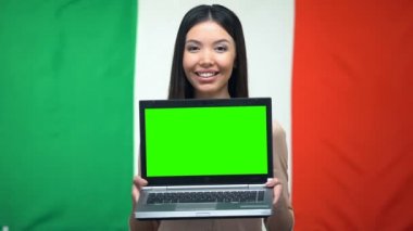 Yeşil ekran ile kadın holdıng laptop, arka planda Italyan bayrağı, göç