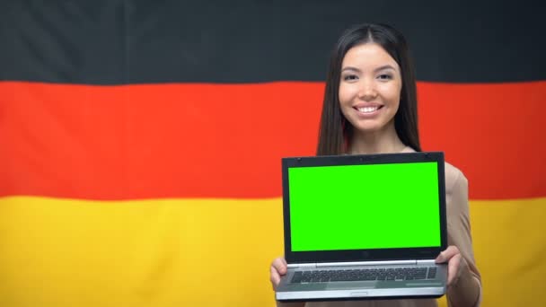 緑色の画面、背景にドイツの旗、旅行とラップトップを保持している女の子 — ストック動画