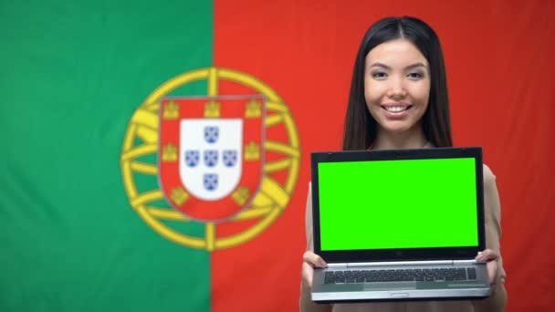 Θηλυκό μαθητή κρατώντας φορητό υπολογιστή με πράσινη οθόνη, πορτογαλική σημαία στο παρασκήνιο — Αρχείο Βίντεο