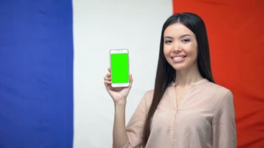 Yeşil ekran ile akıllı telefon gösteren Lady, arka planda Fransız bayrağı, seyahat uygulaması