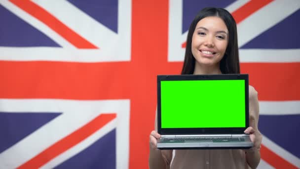 Donna che mostra computer portatile con schermo verde sullo sfondo bandiera britannica, studio — Video Stock