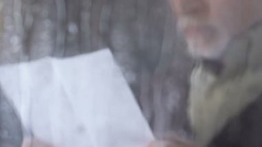 Yağmurlu pencere yakınında mektup okuma kıdemli adam ve iç çekme, ayrılık, boşanma