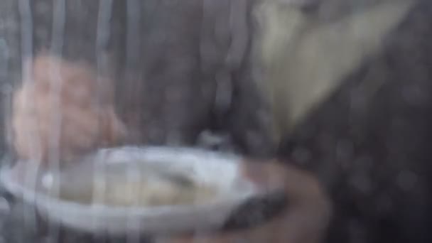 Плохой человек ест овсянку и смотрит на дождь из окна, здоровый завтрак — стоковое видео