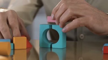 Yaşlı hasta adam titreyen elleri ile renkli ahşap küpler ev yapma, rehabilitasyon