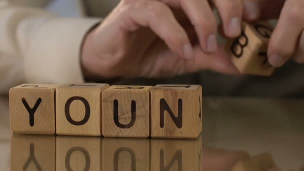 Молодой, пожилой человек делает слова из деревянных кубиков, воспоминаний, желания быть моложе — стоковое видео