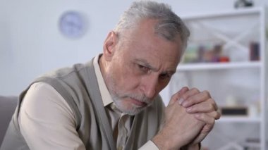 Rehabilitasyon merkezinde oturan ve sağlık sorunları hakkında düşünen yaşlı adam