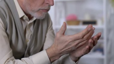 Rehabilitasyon merkezinde titreyen ellere bakan yaşlı erkek, parkinson hastalığı