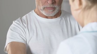 Hemşire yaşlı adam dumbbell ile elini kaldırmak için yardım, ameliyattan sonra rehabilitasyon