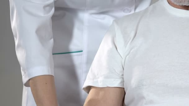 Nurse helping old man with trembling hands holding dumbbells, rehabilitation — Stock Video