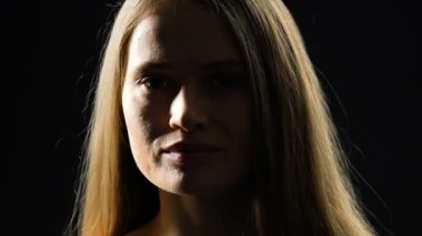 Kameraya bakan kendinden emin bayan, karanlık arka planda izole edilmiş, doğal güzellikte