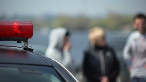 Женщина-полицейский приезжает на место преступления, выходит из машины и идет к свидетелям — стоковое видео