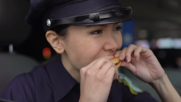 ハンバーガーを食べる不快な味を感じるパトロール女性、ストリートフードの低品質 — ストック動画