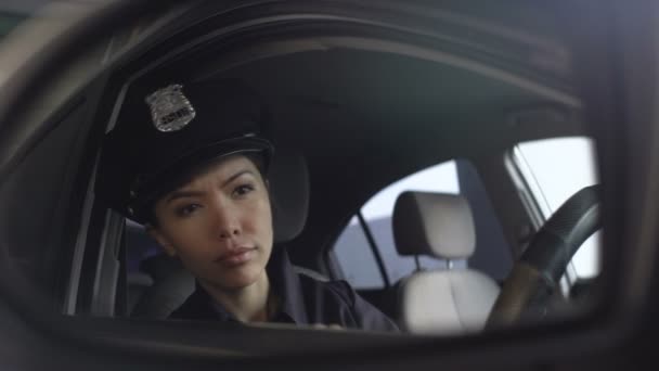 Азіатський офіцер поліції коригування її рівномірної шапки дивлячись на дзеркало заднього виду — стокове відео
