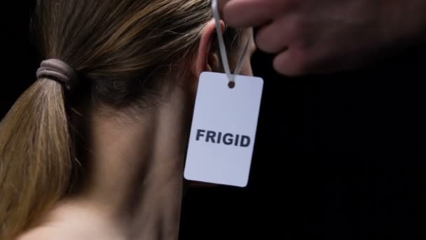 Male hand hanging frigid label on female ear, humiliating personality, offence — Stock Video