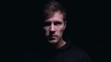 Çılgın sırıtış ile tehlikeli adam karanlık arka plan karşı kamera içine bakıyor