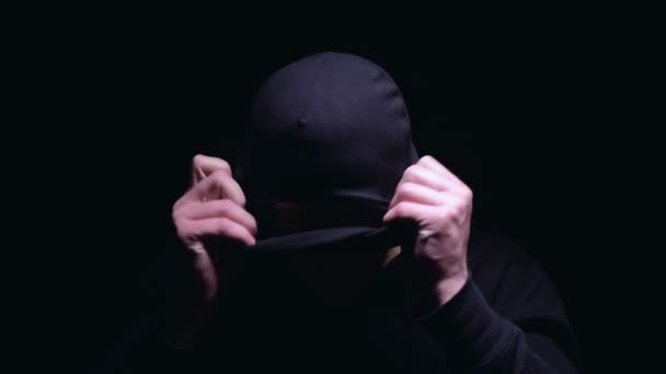 Серйозна людина надіває Балаклаву, готується до вбивства або пограбування, бандитизм — стокове відео