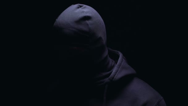 罪犯在黑暗的巴拉克拉瓦愤怒地看着镜头的黑色背景 — 图库视频影像