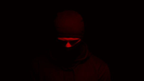 戴面具的男子站在闪烁的红灯下，自杀式炸弹袭击者，恐怖主义 — 图库视频影像