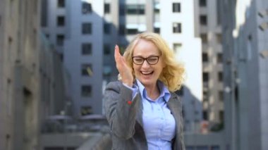 Ofis binası dışında dans overjoyed kadın yönetmen, promosyon kutluyor