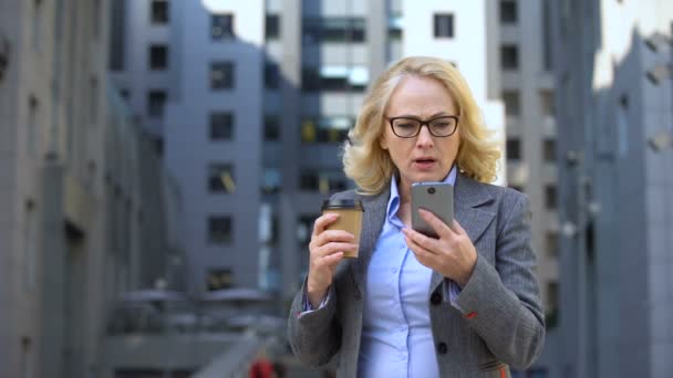 心配した女性マネージャーがコーヒー、技術を持ってスマートフォンのニュースを読む — ストック動画