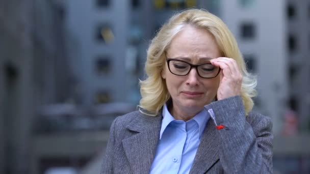 Depressed female worker crying taking eyeglasses off, work dismissal, retirement — Stock Video