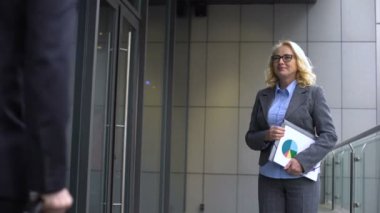 Gülümseyen yaşlı iş kadını genç erkek çalışanla tanışıyor, ortaklar el sıkışıyor