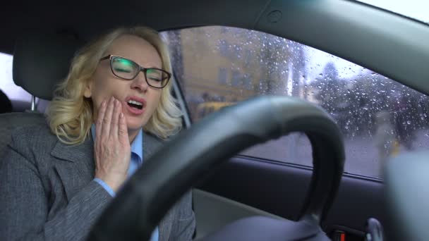 Senior female in business suit feeling toothache driving work car, health care — Stock Video