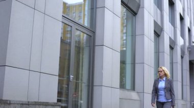 Üzgün yaşlı kadın pencere cam yansıması görünümlü, ofis binası boyunca yürüyüş